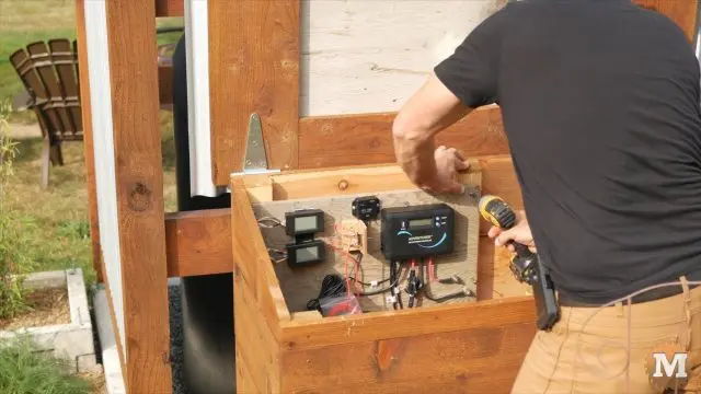 attaching board to wall of mini off grid pump house