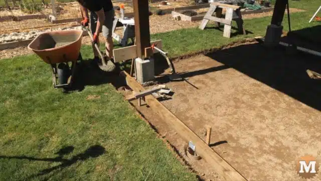 Shovelling wet concrete into tub for deck foundation