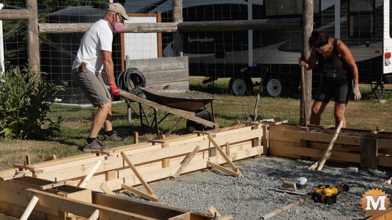Pouring concrete into forms with a mixer and wheelbarrow