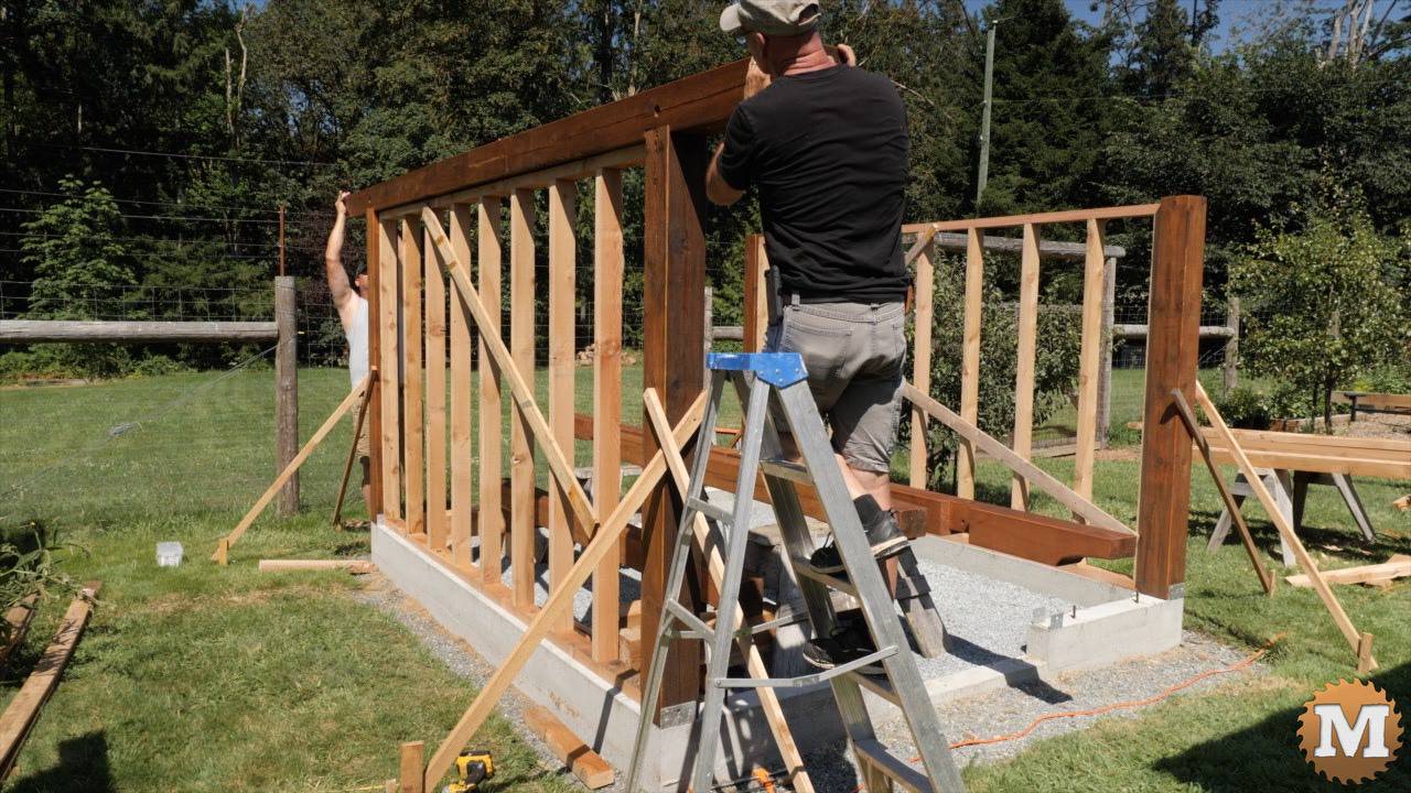 A beam lifted over posts and a stud wall for a greenhouse