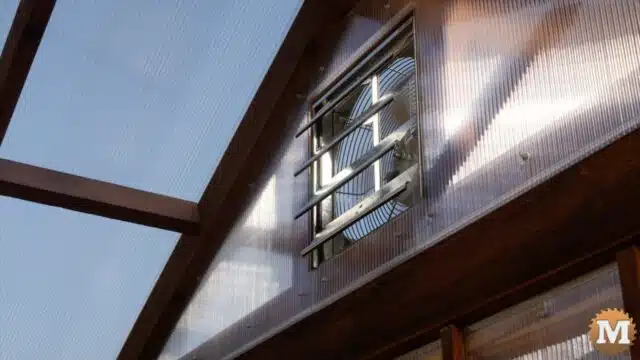 A greenhouse fan louvers in a gable