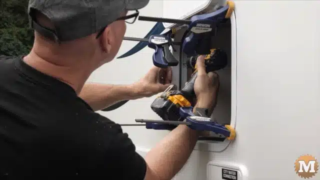 Attaching the compartment door frame to the camper wall with screws