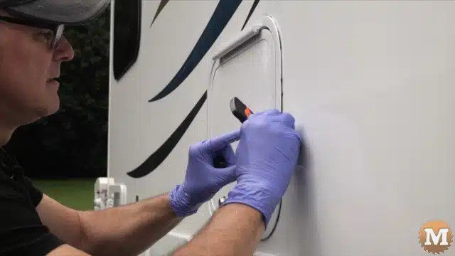 Scraping any excess butyl tape with a plastic razor blade