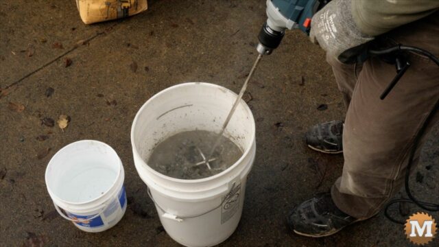 mixing concrete in a pail with a blender attachment on a high-torque drill