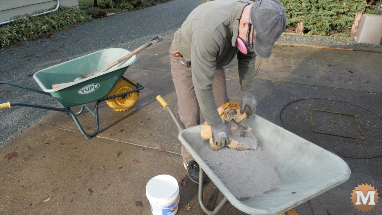 adding most of the 60 pound bag of concrete to the wheelbarrow