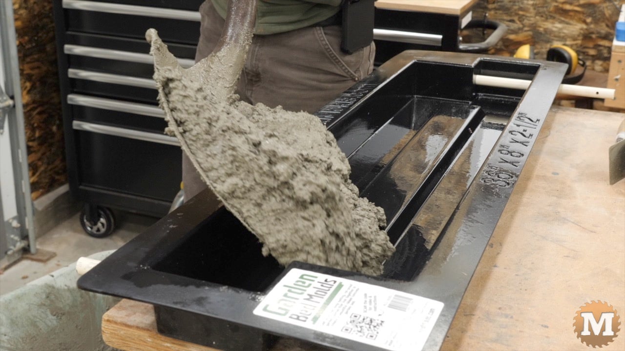 the first few shovelfuls of wet concrete mix going into the mold