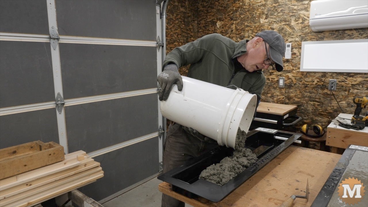 wet concrete is poured from a pail into the mold