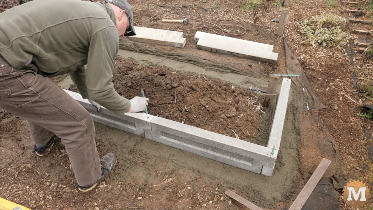 sliding rebar into aligned holes on the wall of the concrete garden bed