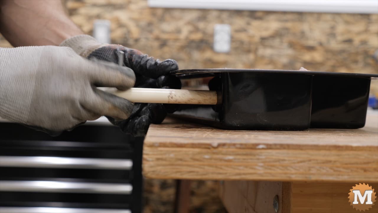 a hand pulling a plastic pipe from a mold