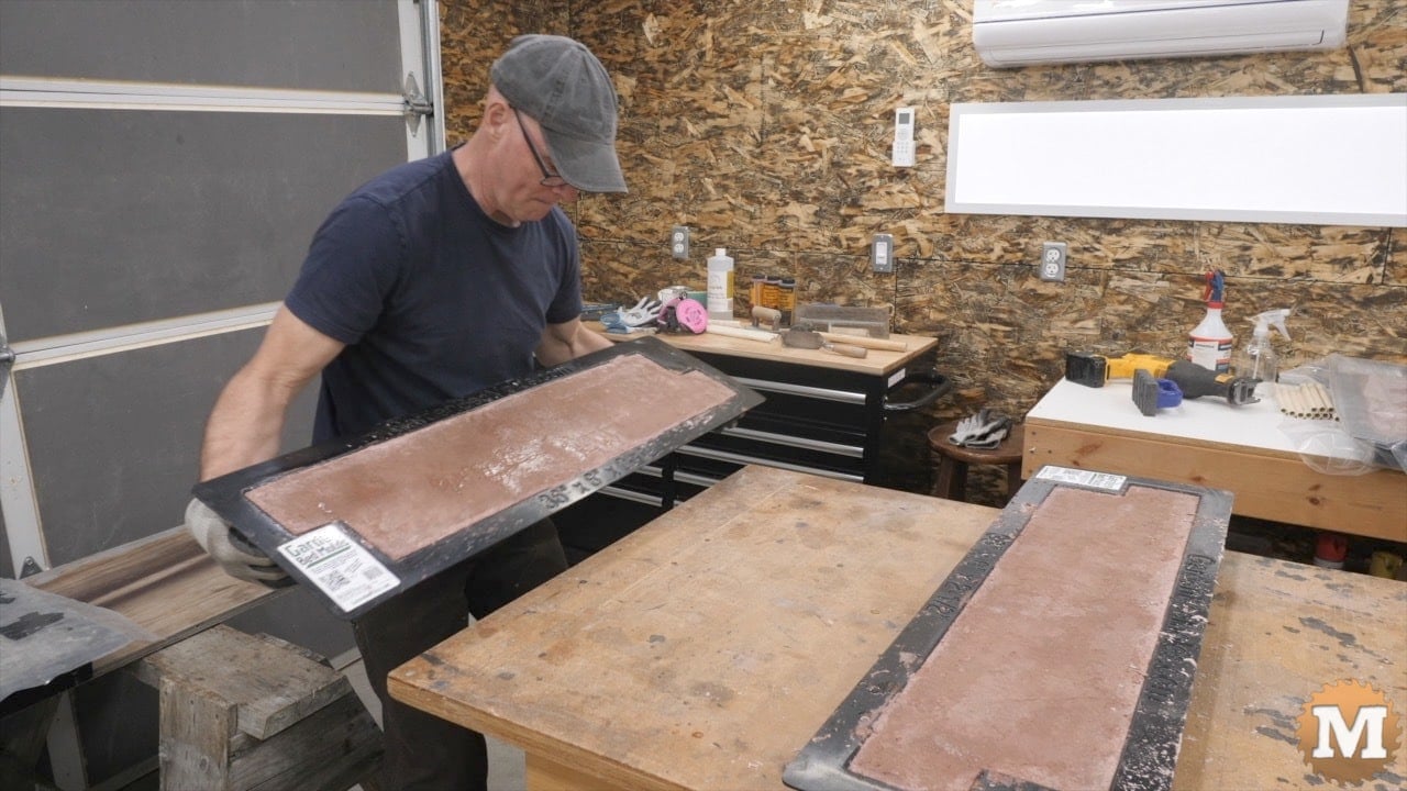 A man lifts a concrete casting in a black plastic mold