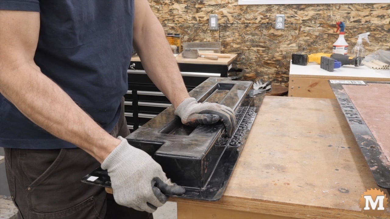 A man trying to remove a concrete casting from its mold