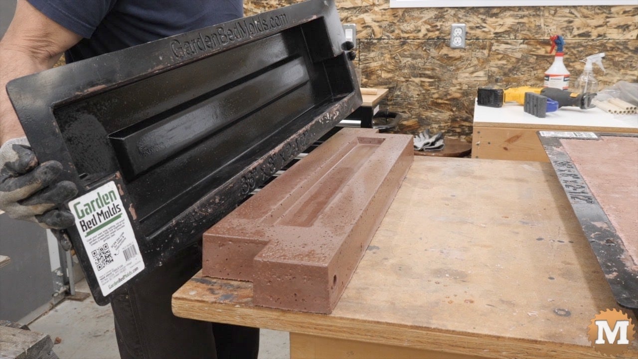 A concrete casting on a bench with a man holding the plastic mold