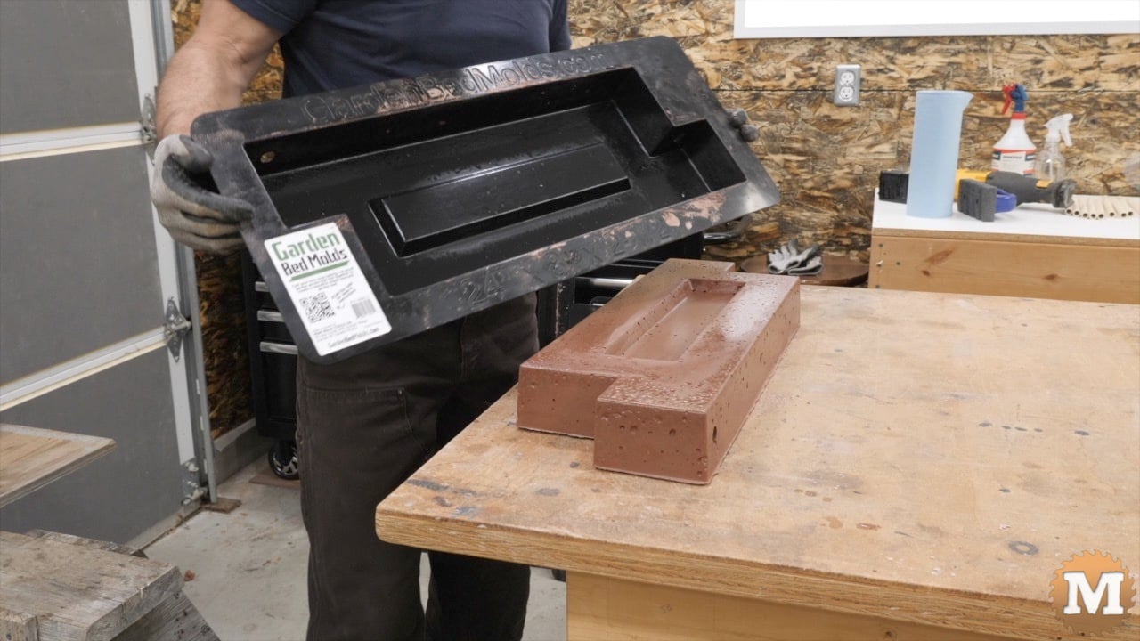 A concrete casting on a bench with a man holding the plastic mold