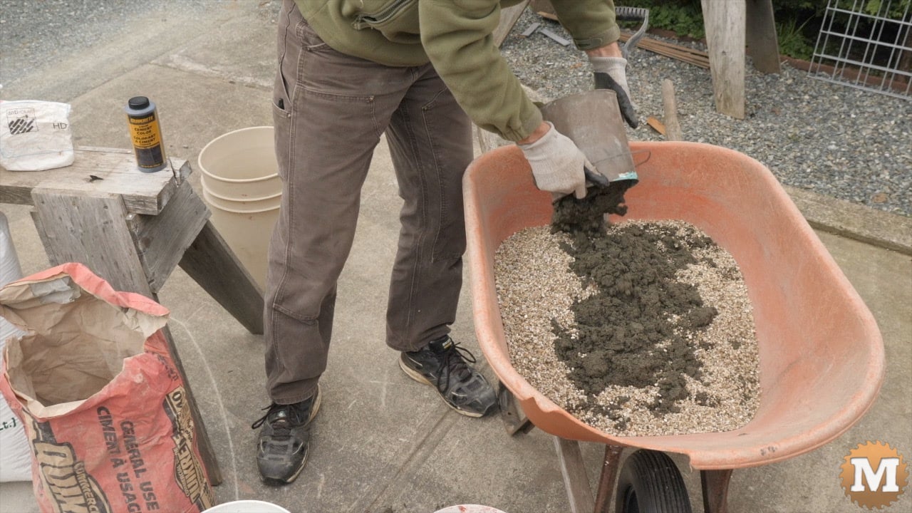 A man adding sand to a wheelbarrow