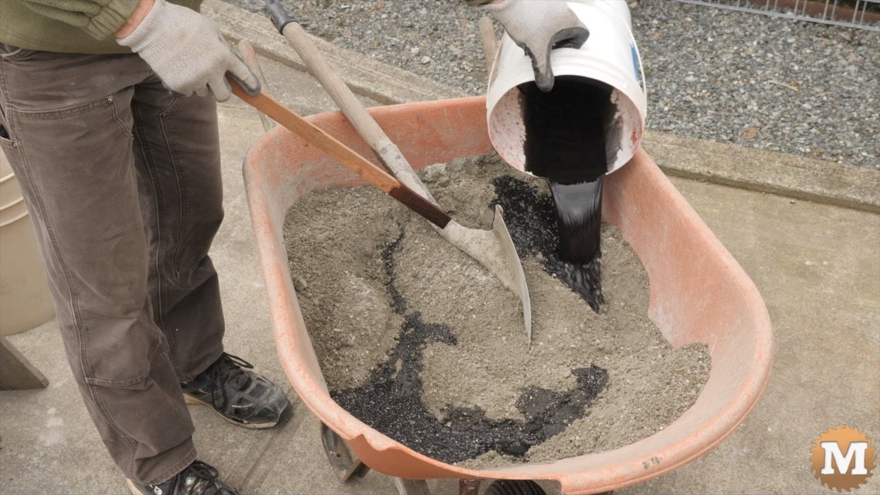 Pouring dark water from a pail onto vermiculite and sand in a wheelbarrow