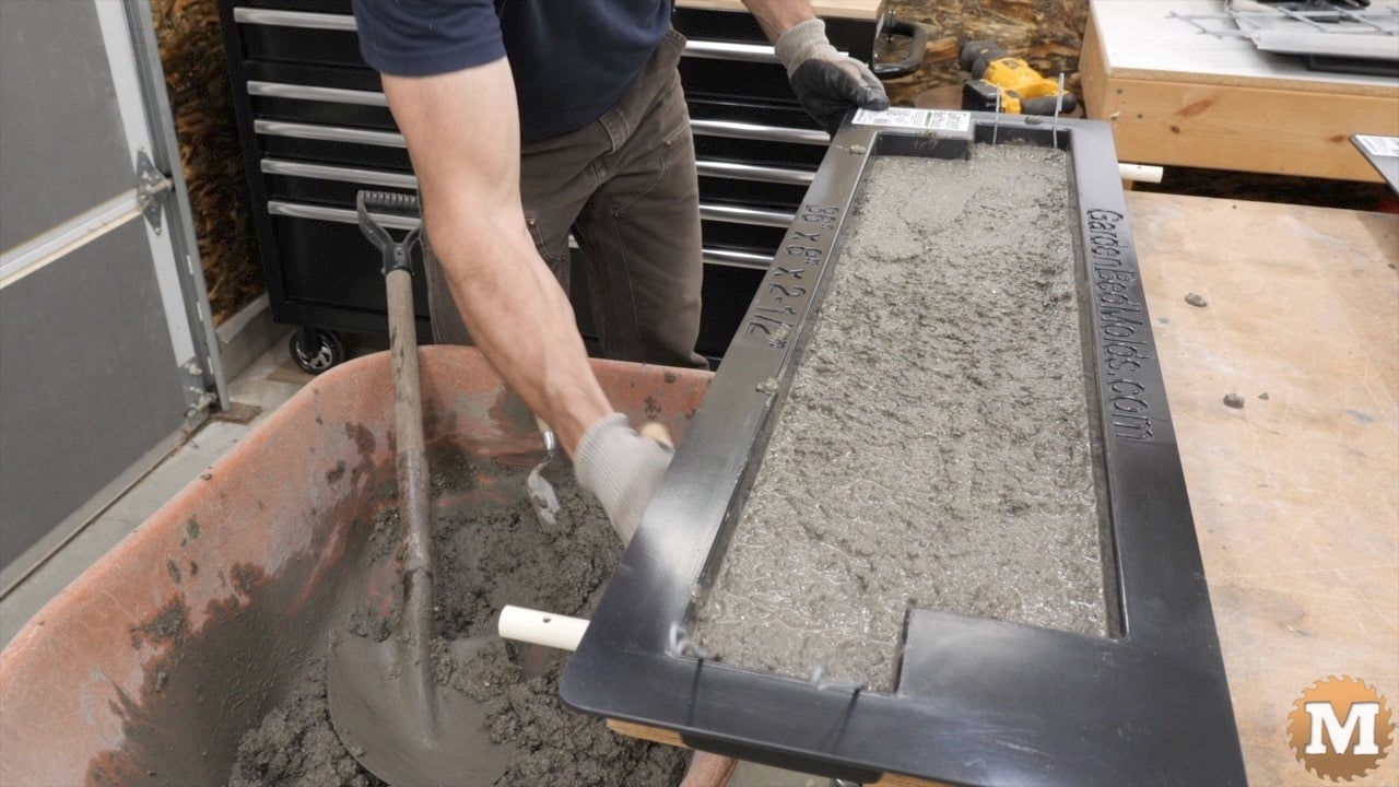 Tapping the underside of the bench with a rubber mallet to settle the concrete
