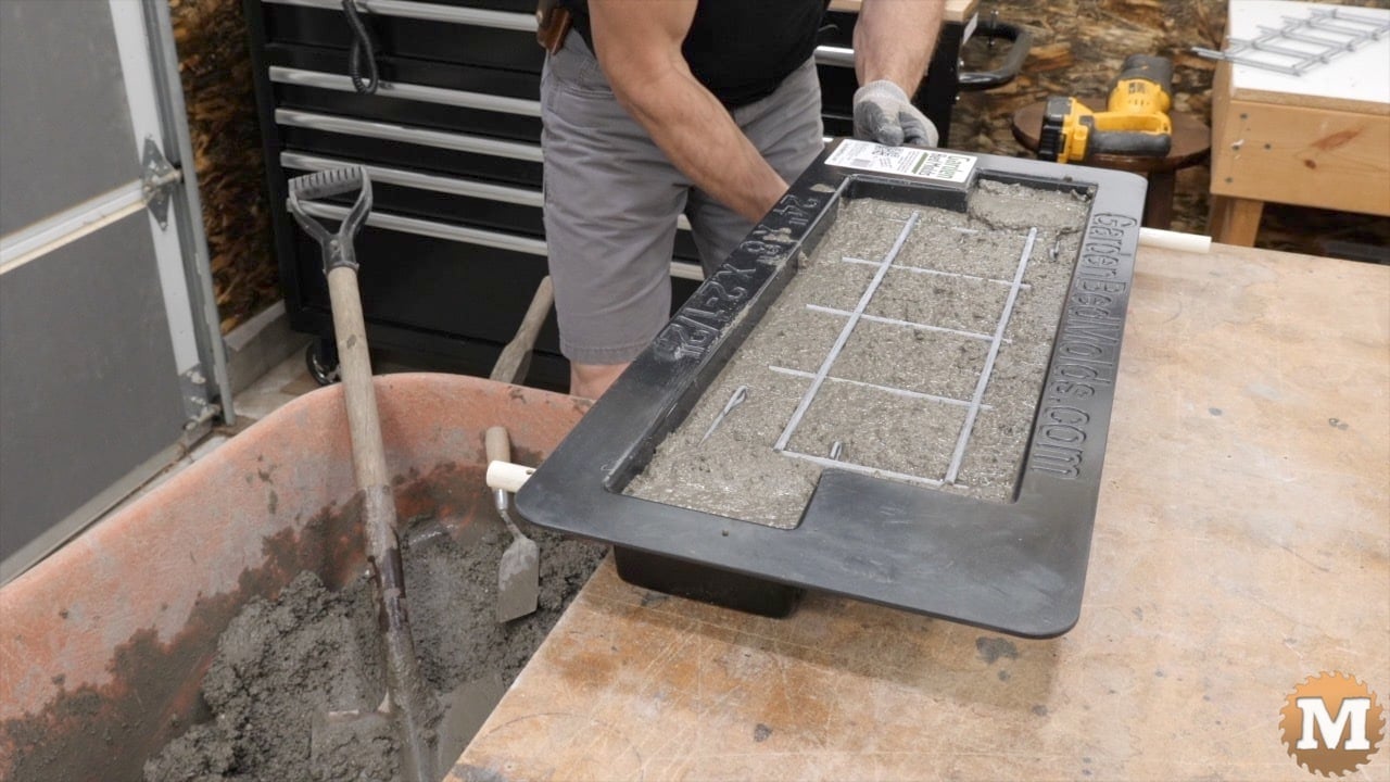A wire mesh sitting in fresh wet concrete being added to a plastic form