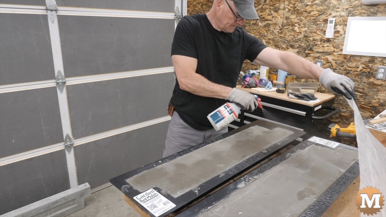 A man sprays water onto cast concrete panels in a mold