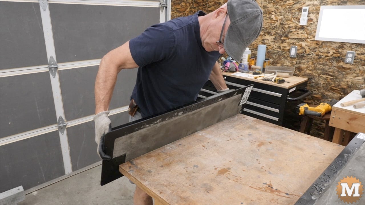 a man holding a concrete mold in front of a workbench