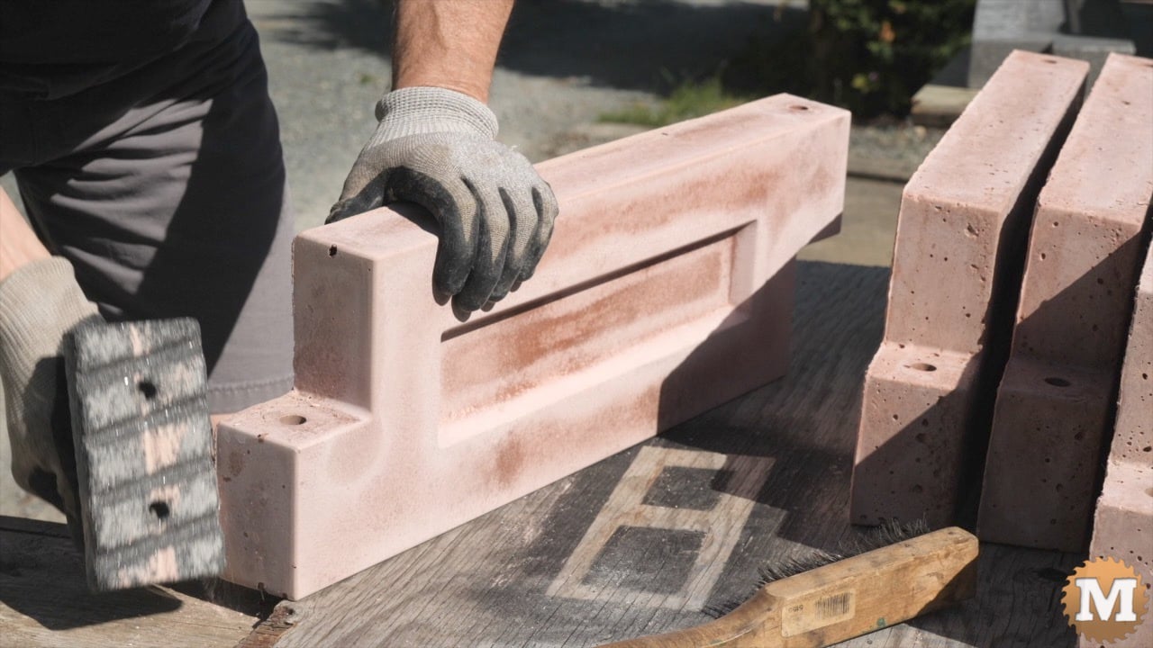 a man holding a concrete polishing tool beside a cast concrete panel