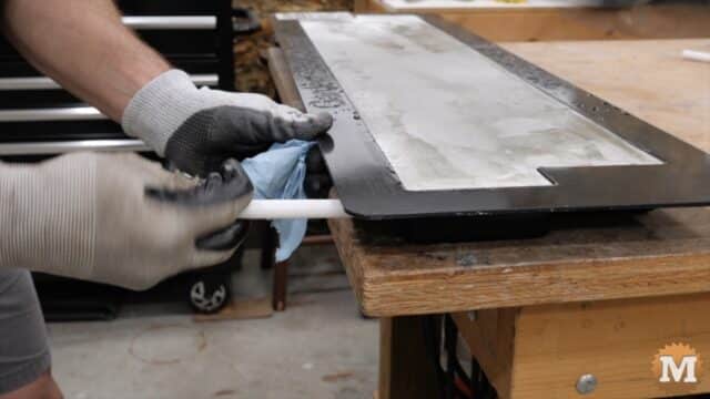 gloved hands pulling a plastic pipe from a concrete mold