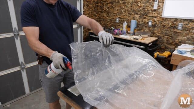 a man spraying water on new concrete under plastic sheet