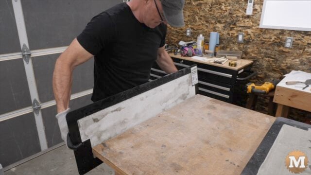 a man holding a concrete mold against a workbench