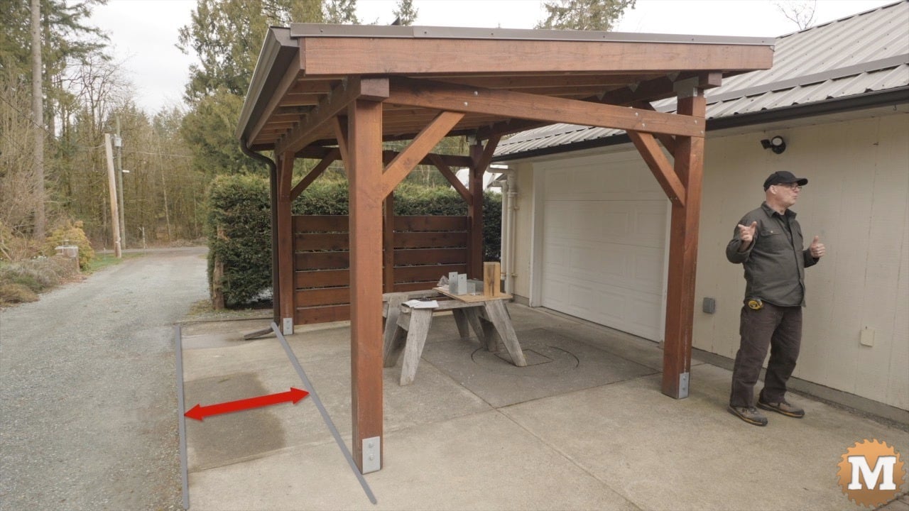 A man talking in front of a wooden lean-to structure