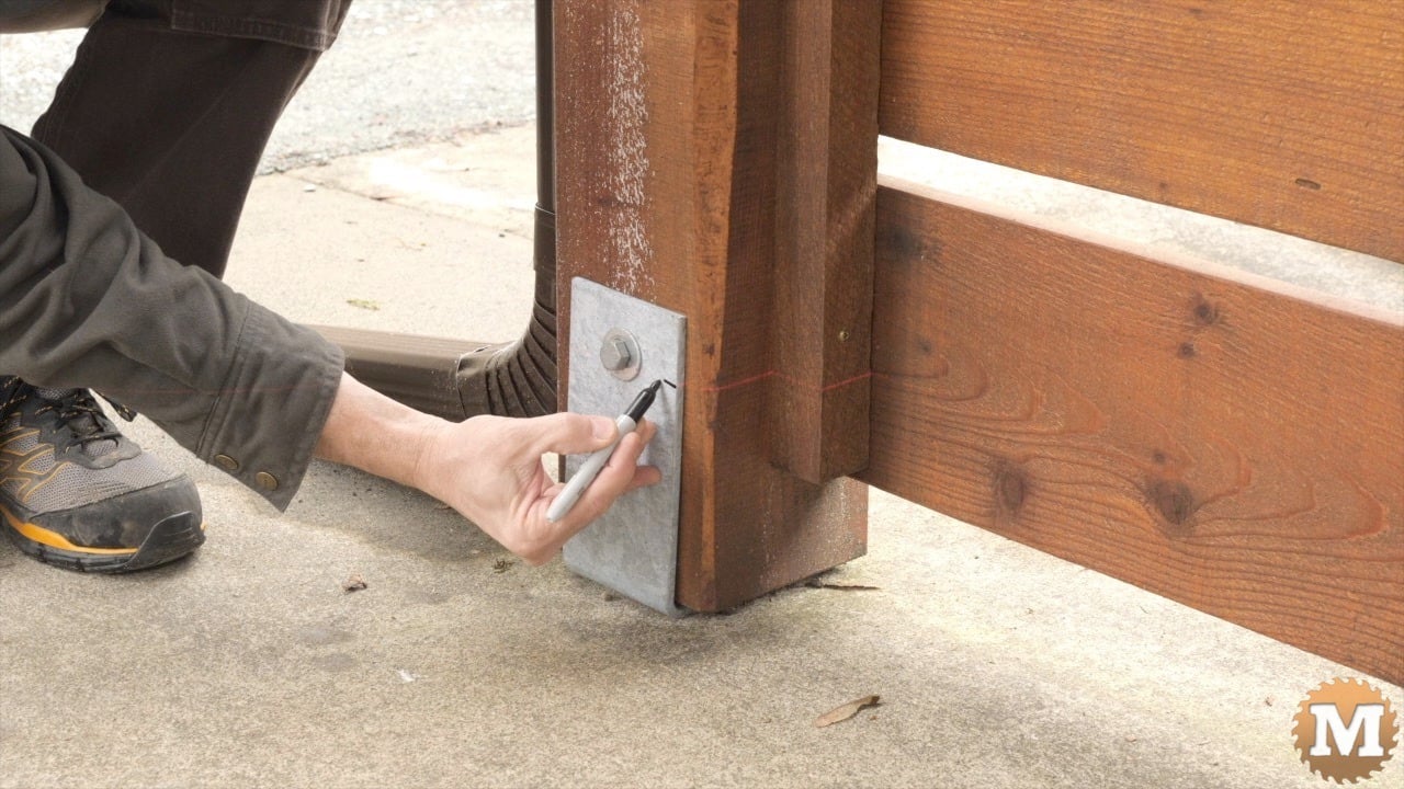 A man marks a post saddle with sharpie