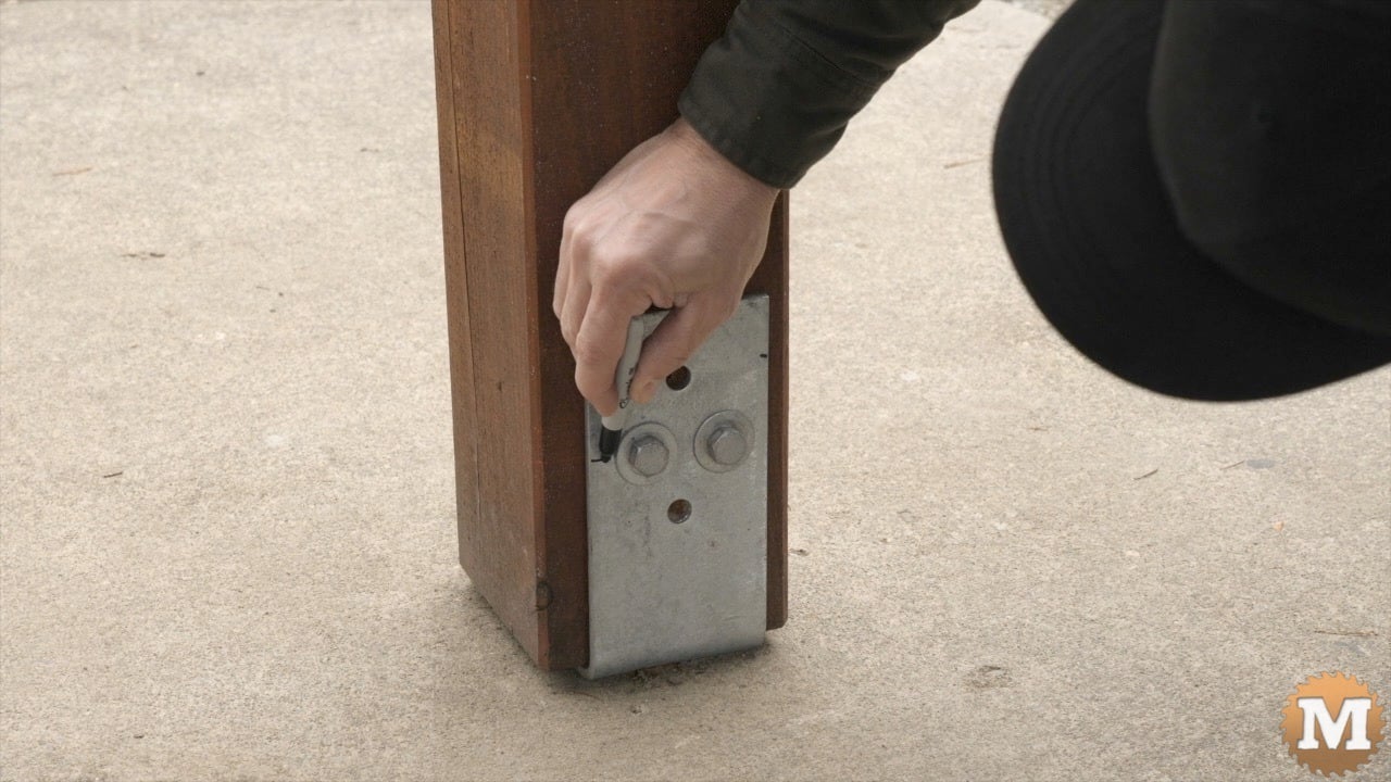A man marks a post saddle with sharpie