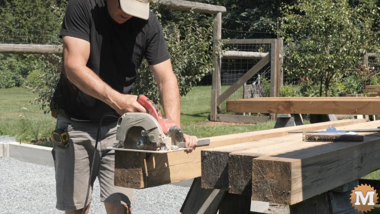 A man using a circular saw to cut a 6x6 post