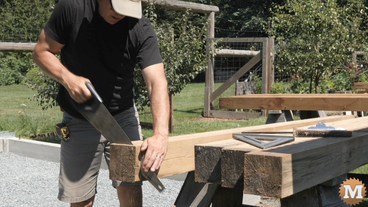 A man using a handsaw to cut a 6x6