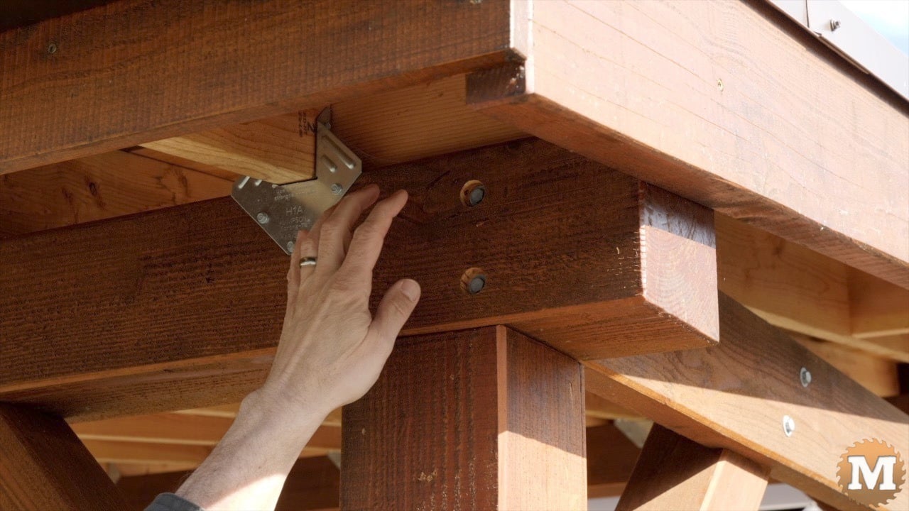 A man pointing to lag bolts in a beam