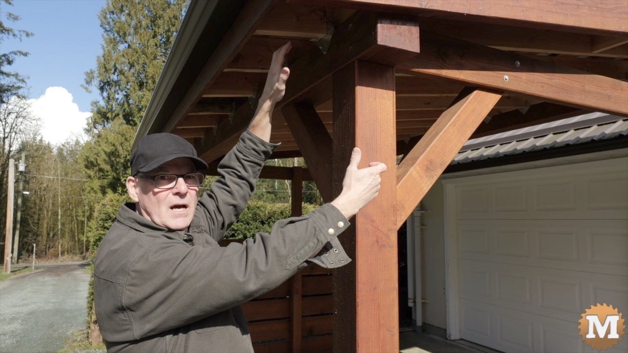 A man indicating parts of a wooden pavilion