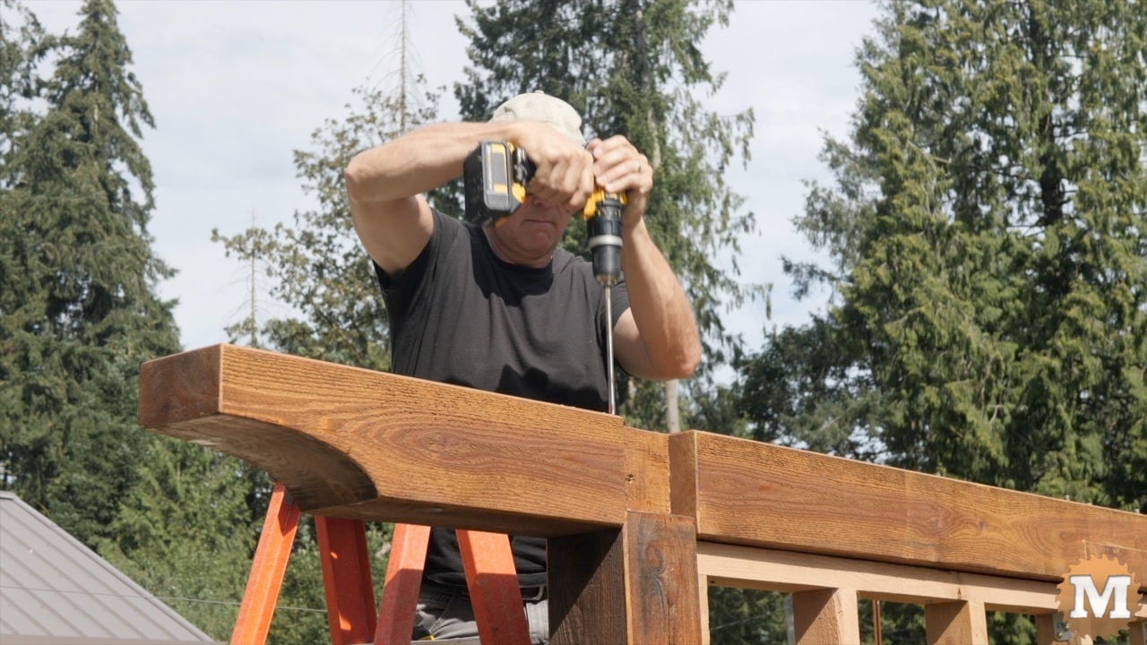 A man drilling into a beam with a long drill bit