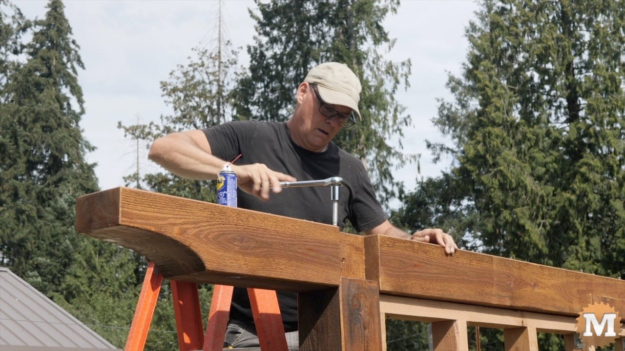 A man ratcheting a lag bolt in a post and beam project
