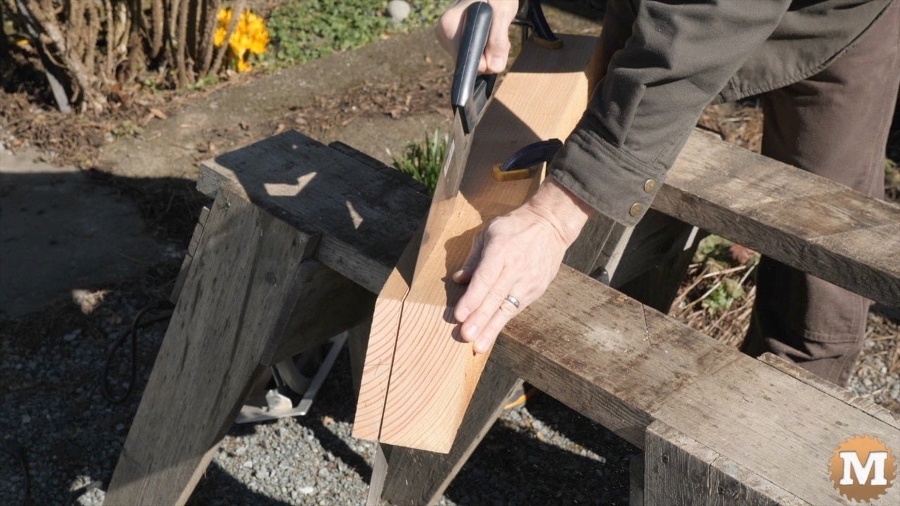 A man sawing wood across sawhorses