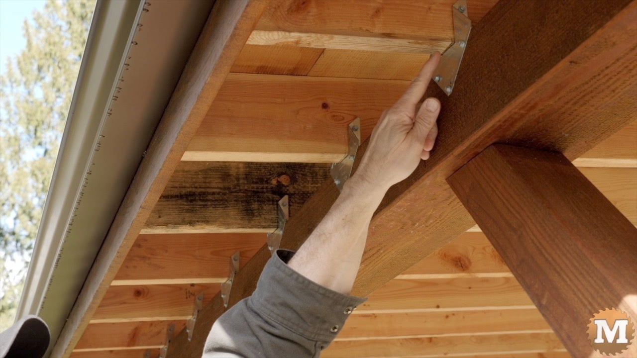 a hand pointing at a wooden beam