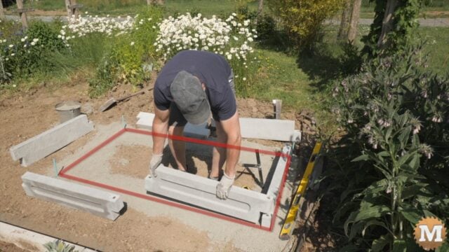 A man assembling a concrete garden bed