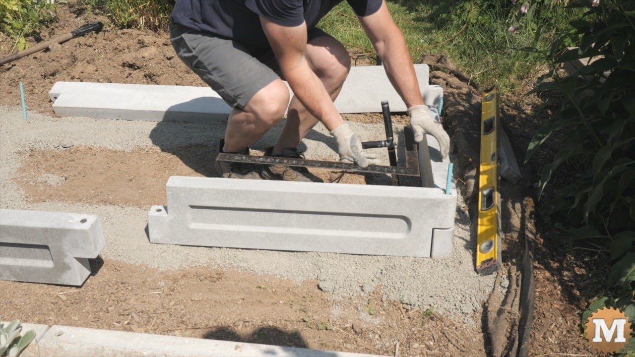 A man assembling a concrete garden bed