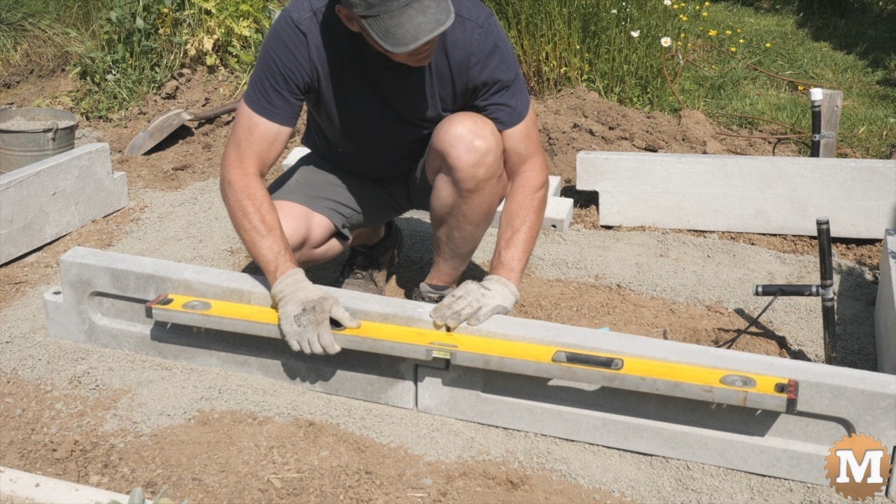 A man assembling a concrete garden bed