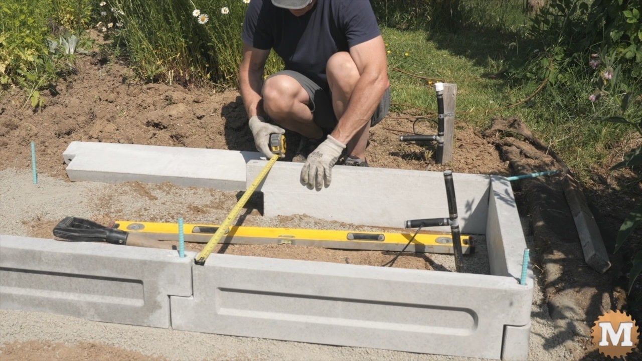 A man assembling a concrete garden bed