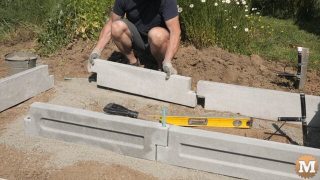 A man assembling a concrete garden bed