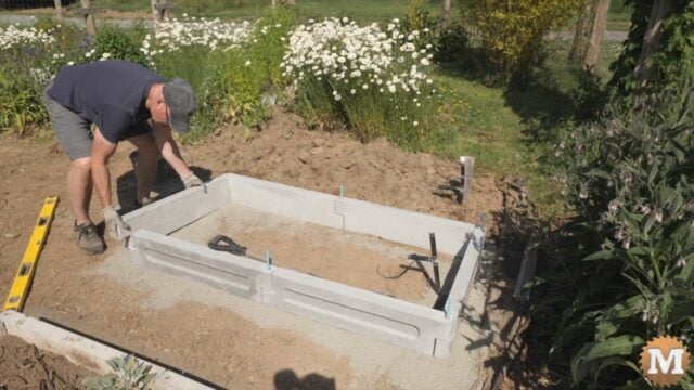 A man assembling a concrete garden bed