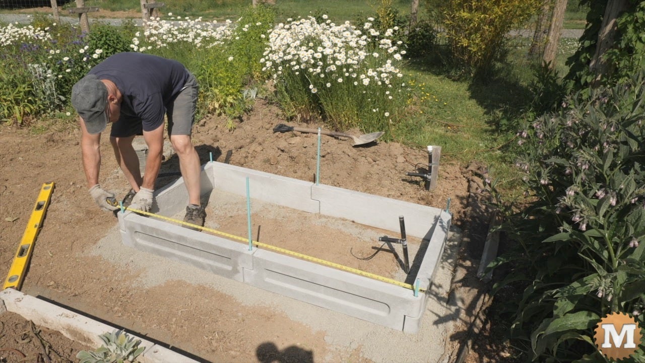 A man assembling a concrete garden bed