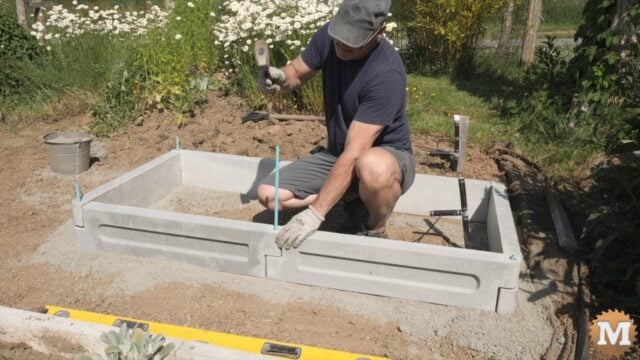 A man assembling a concrete garden bed