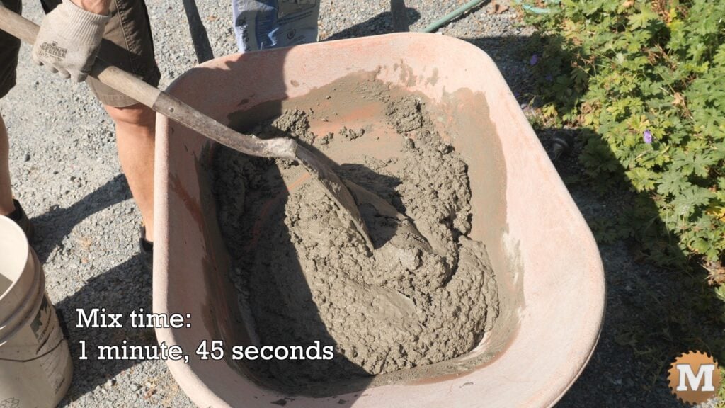 mixing concrete in a wheelbarrow with a shovel