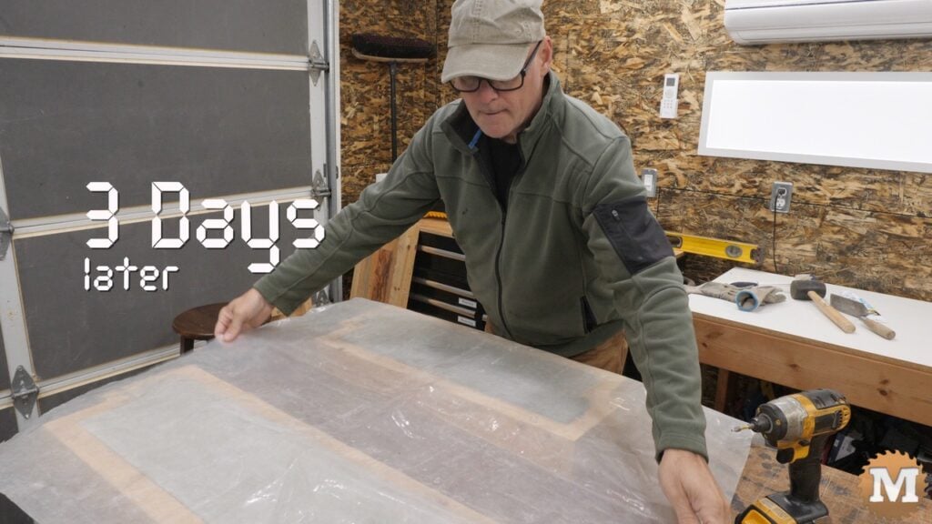 A man removing a plastic sheet from concrete molds on a worktable
