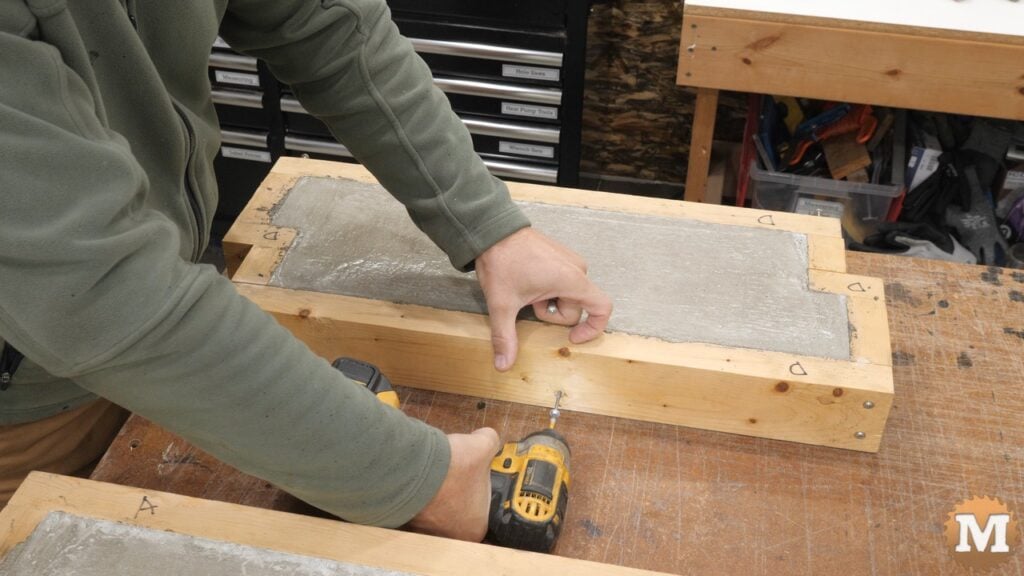 A man removing screws from a DIY concrete casting wooden mold