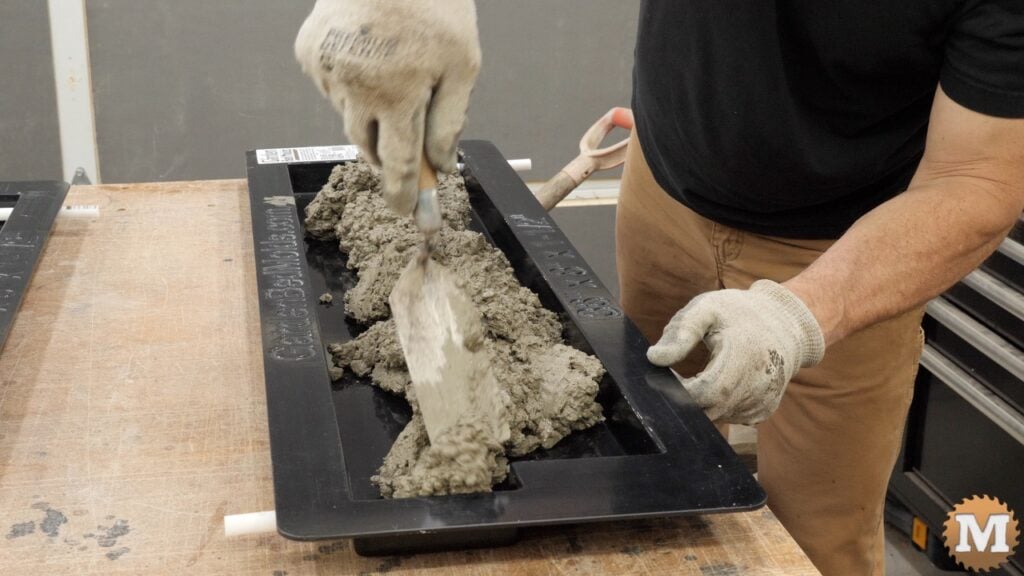 fresh wet concrete being added to a plastic casting mold on a workbench